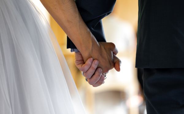 Brudparet ses bakifrån, hand i hand.