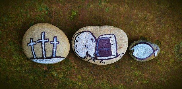 Tre målade stenar med kors, sten, bibel och bröd.