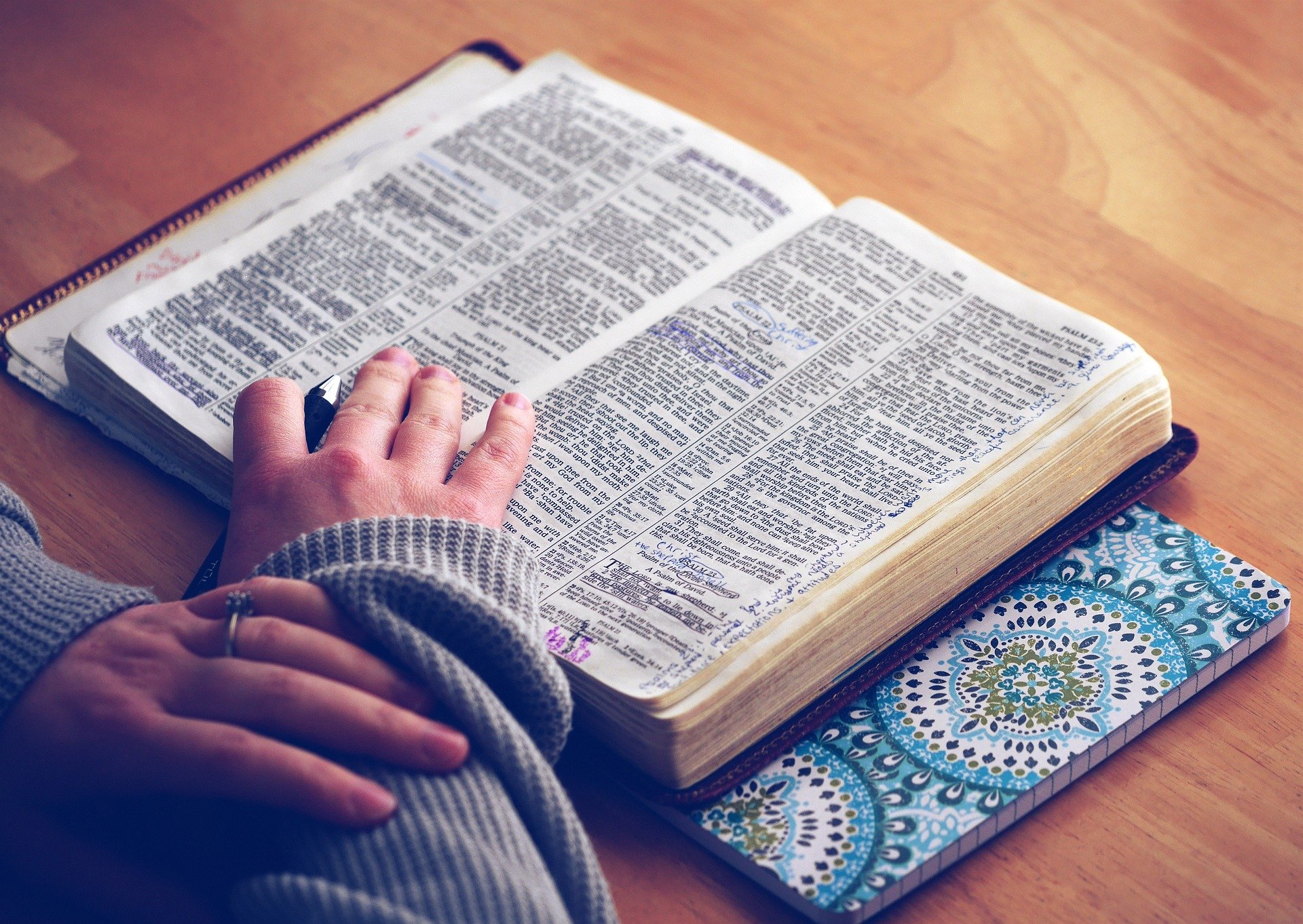 The message club PÅ bilden finns en bibel. En person håller händerna på den.
