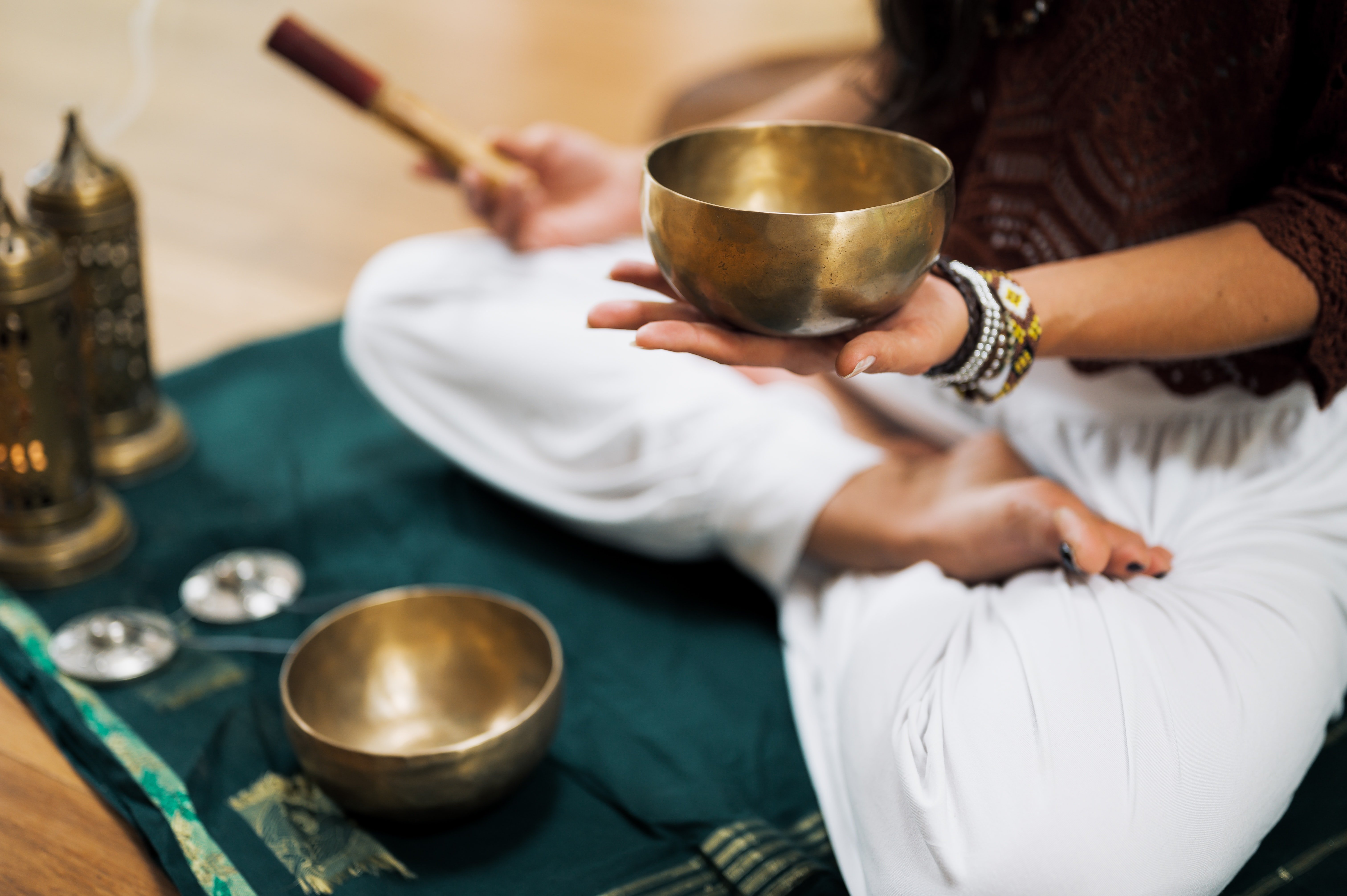 Stilla morgonbön med hela kroppen Benen i kors för en människa som sitter på golvet. Hen spelar meditationens början med en skål.