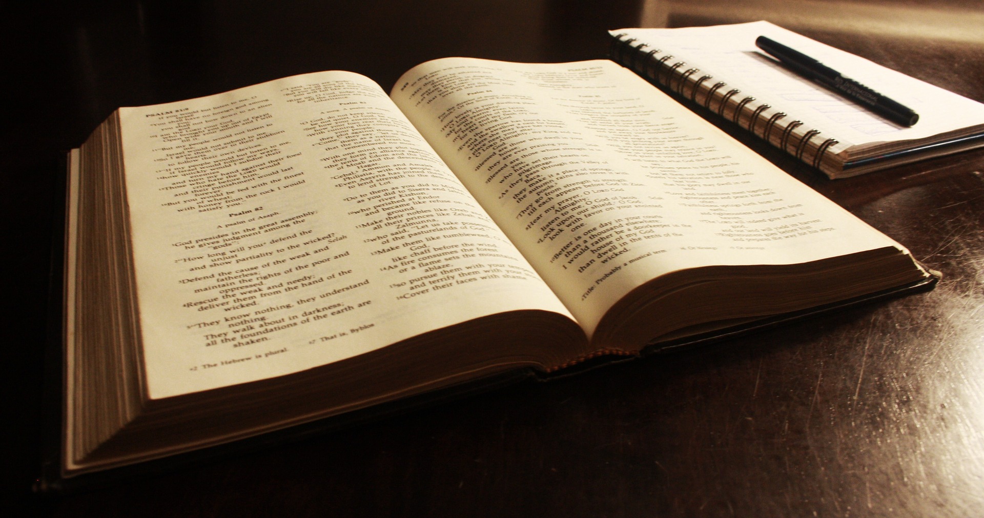 En Bibel som är öppnad och ett anteckningsblock med en penna.