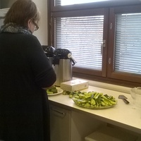 En kvinna skär gurka i köket.