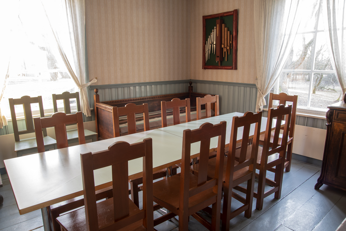 Bagarstugans interiör lilla rummet med träsoffa, bord och stolar sittplats för 10 personer